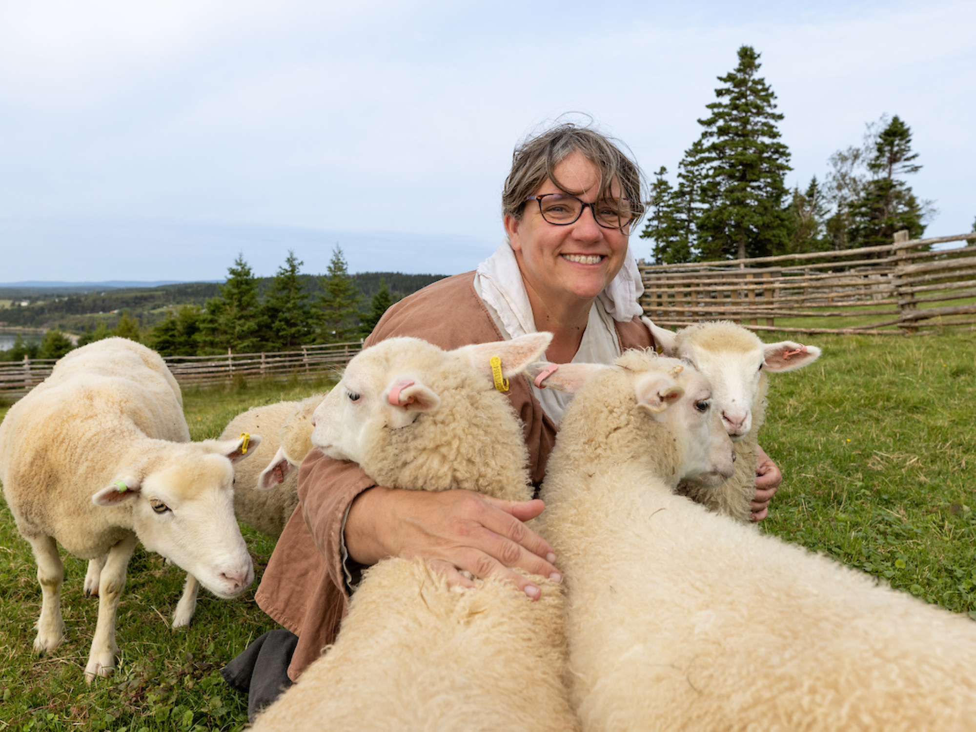 Costumed interpreters, a woman is holding two sheep.